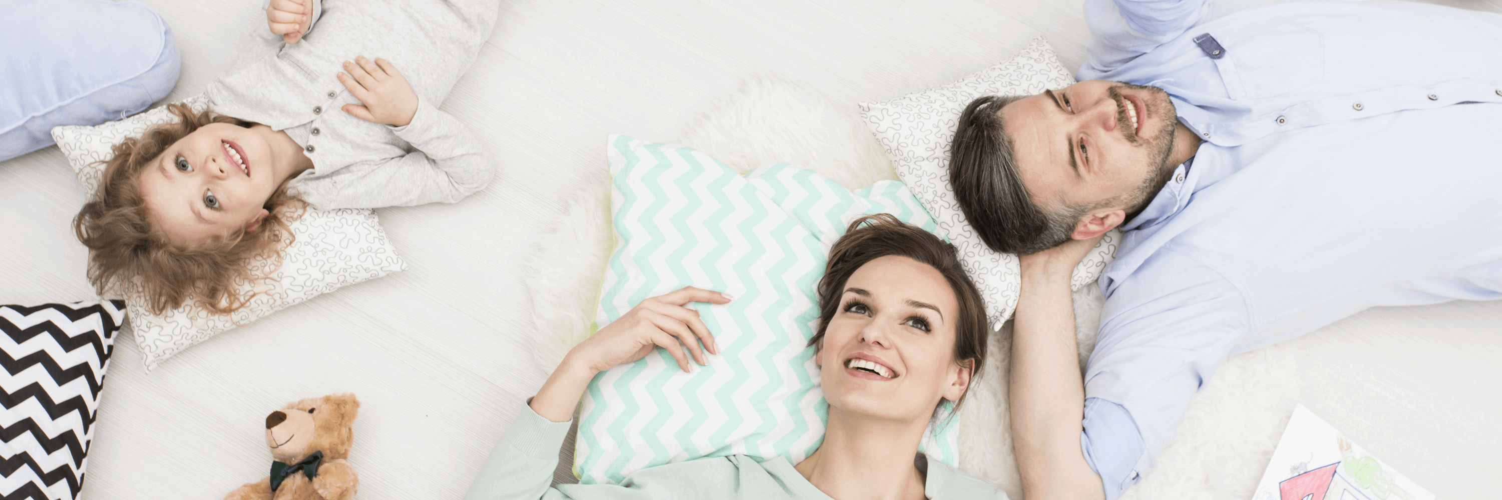 A happy family laying on the bed looking up at us