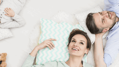 A happy family laying on the bed looking up at us