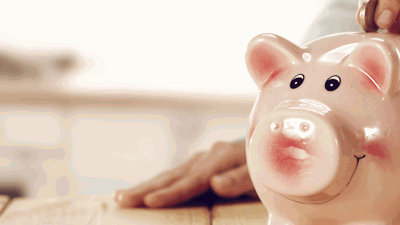 Someone putting money in a piggy bank