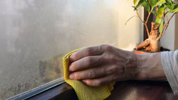 person-wiping-condensation-from-window